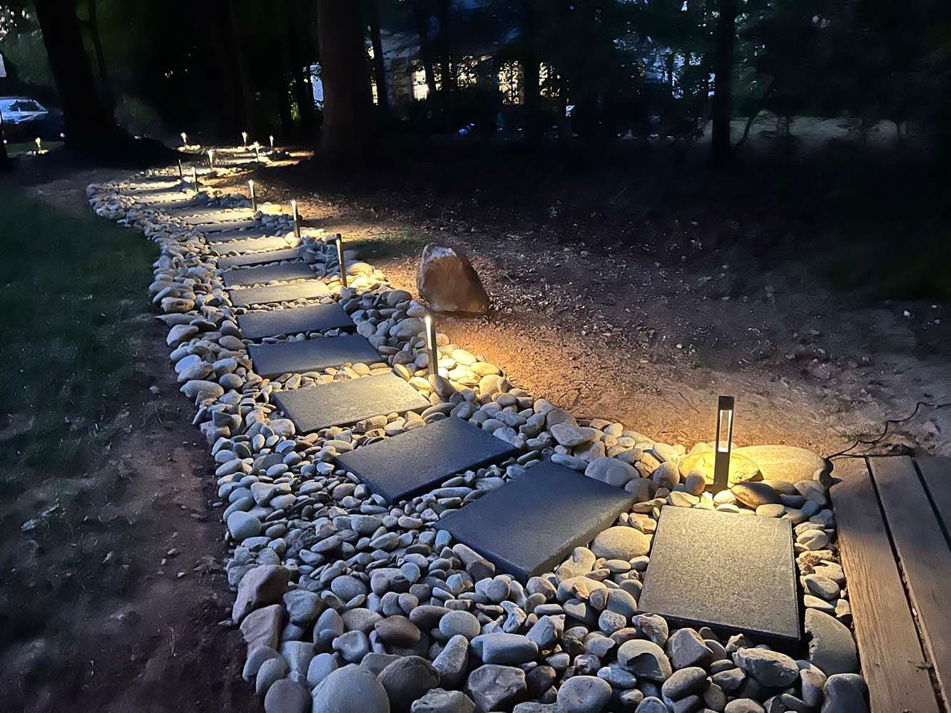 A stone walkway with lights on it is lit up at night.