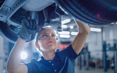 Technician in blue uniform inspecting machinery with a wrench in an industrial workshop