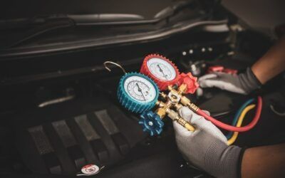 Mechanic connecting red and blue pressure gauges to an engine bay during automotive service