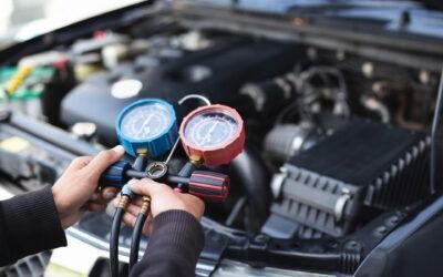 Hands connecting gauges to a car engine for AC or pressure diagnostics