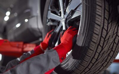 Mechanic in red gloves tightening lug nuts on a car wheel with a wrench