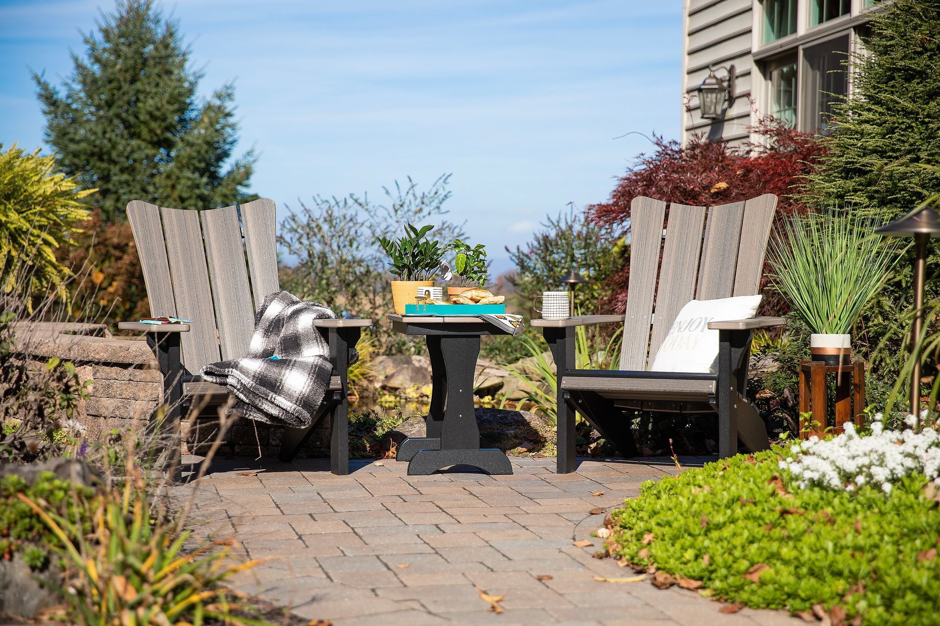 Outdoor setup with two Bayside Adirondack chairs in Coastal Gray and Black made from recycled plastic with a side table.