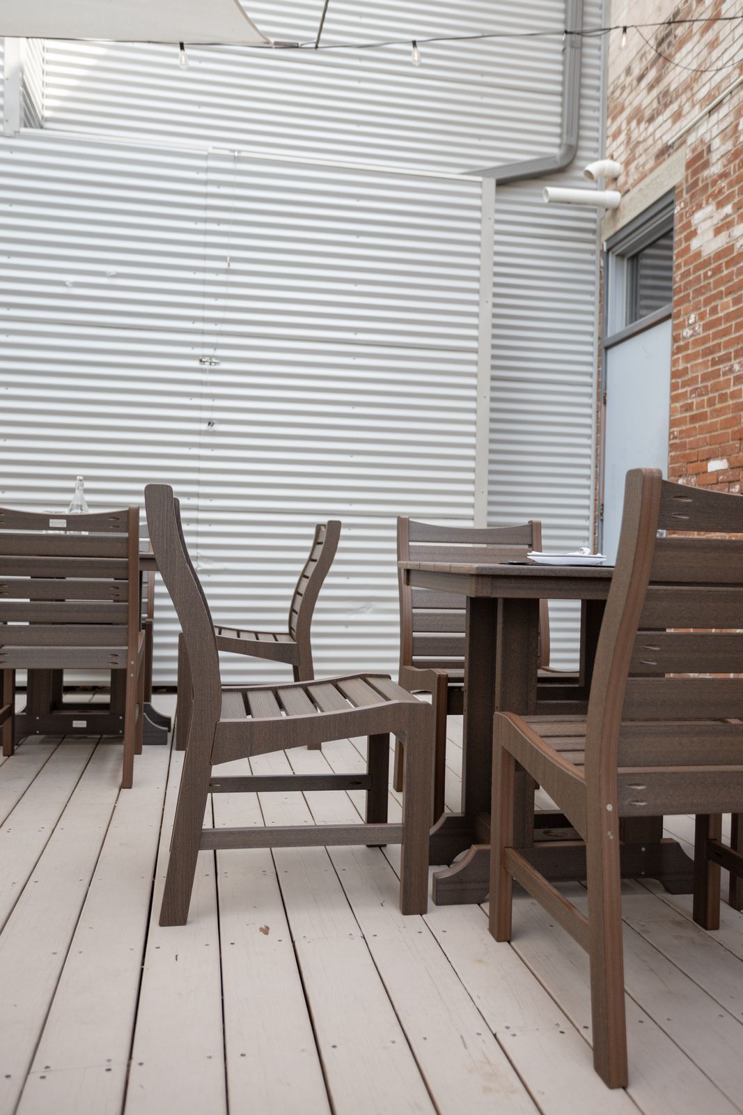 Outdoor patio setup featuring Bristol dining chairs and a Garden Classic 33-inch square table beneath a sun canopy.