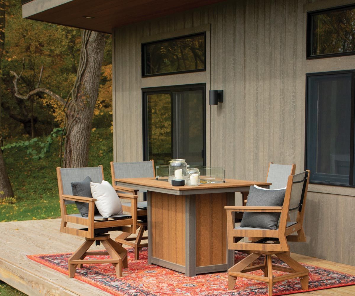 “Donoma 42x54 rectangular fire table in Antique Mahogany and Coastal Gray placed on a cozy porch setting.