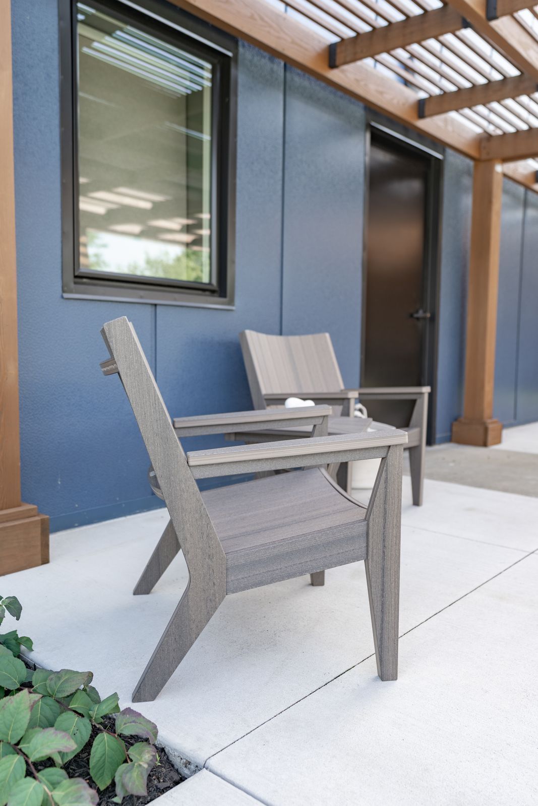 Outdoor Mayhew Chat chairs in Coastal Gray set beneath a covered porch area.