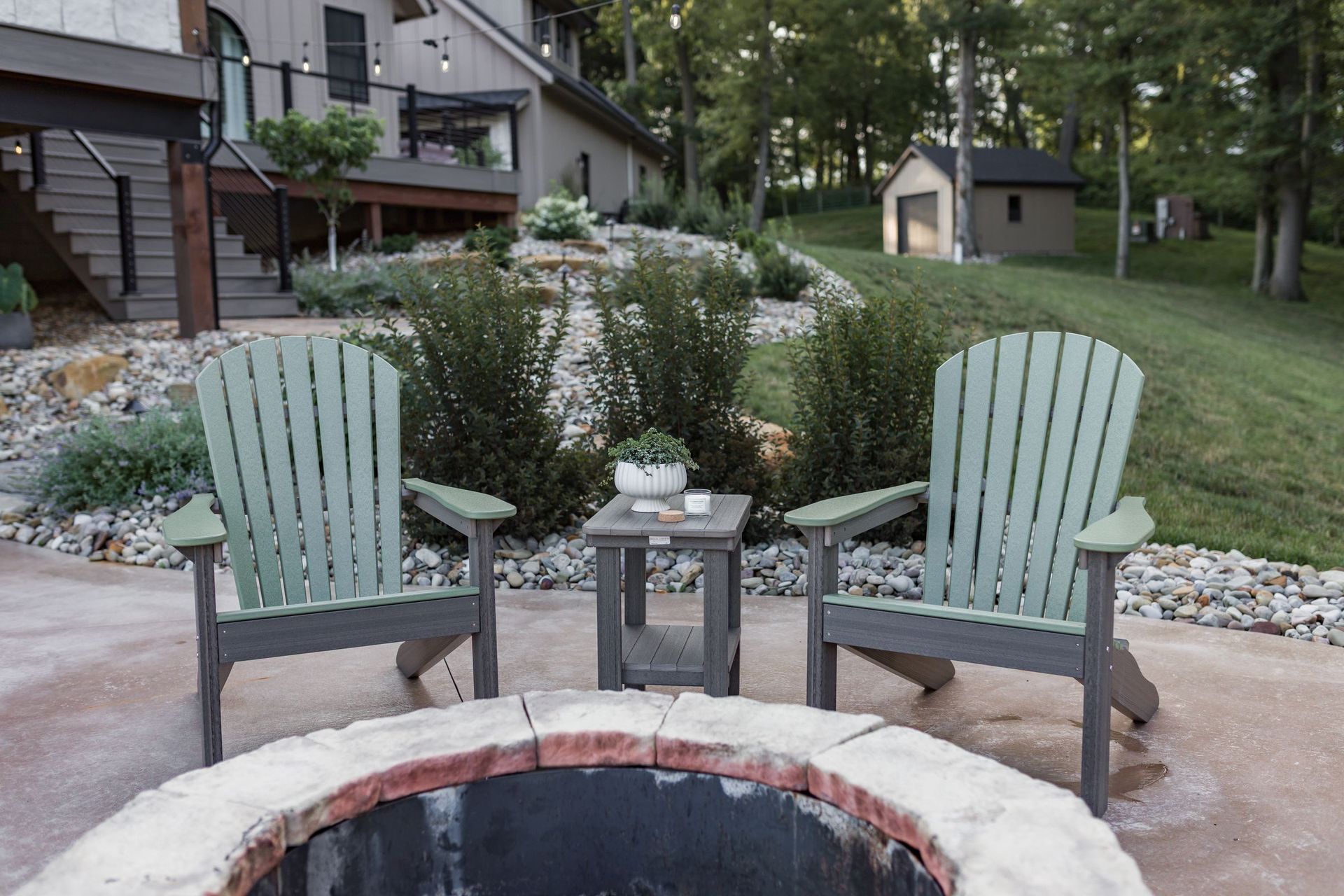 Pair of Sage on Coastal Gray Comfo-Back Adirondack chairs with a matching side table in front of a fire pit.