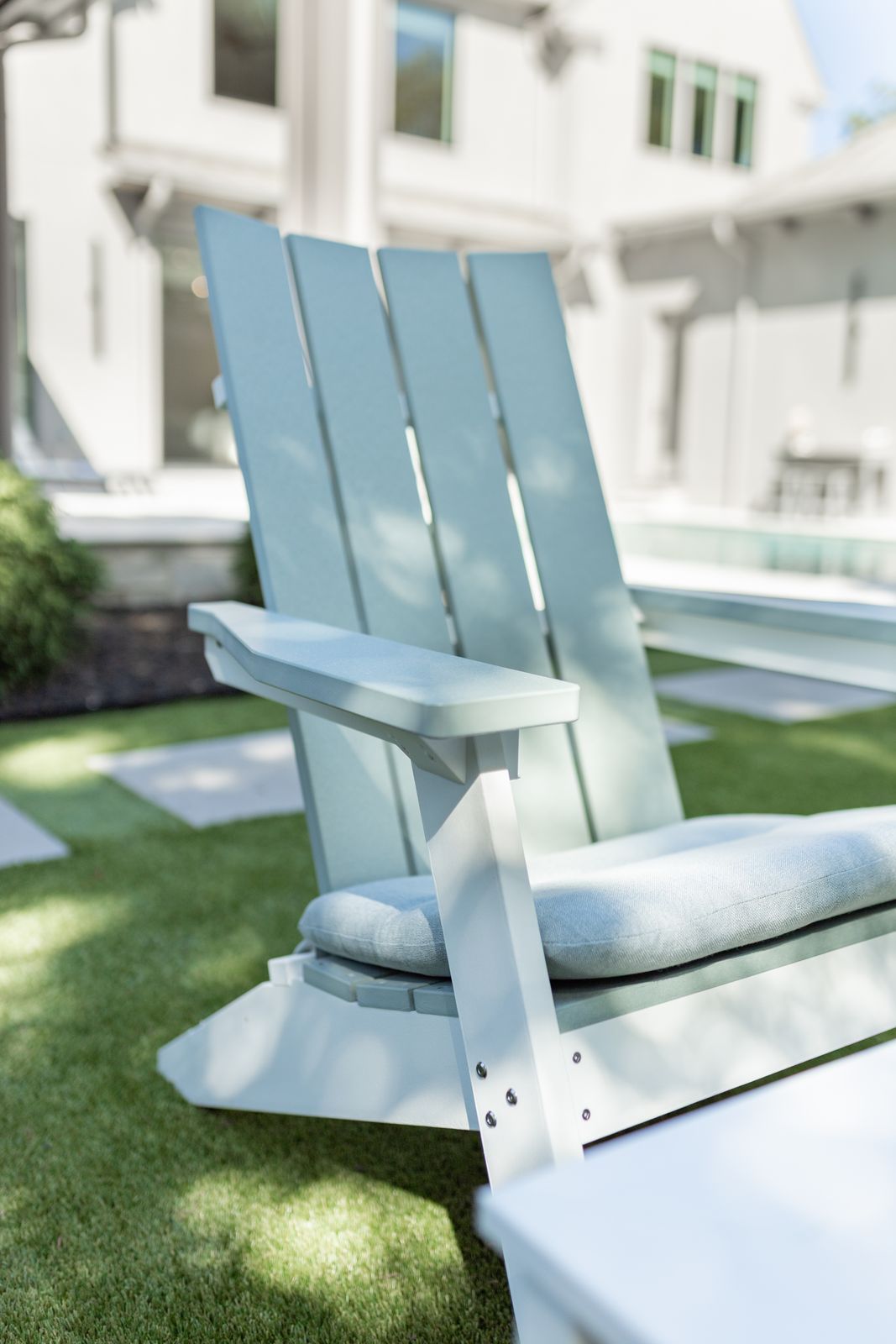 eafoam on White Mayhew Stationary Adirondack chairs made from recycled plastic with seat cushions and coffee table on patio.