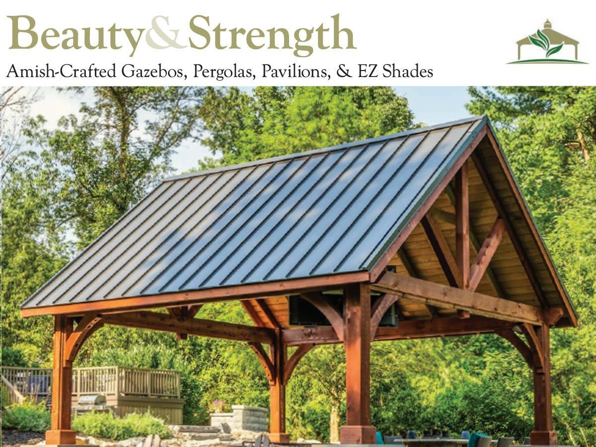 An Amish-crafted wooden pavilion with a dark metal roof, set outdoors among lush green trees.