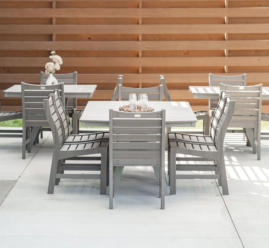 Outdoor dining set with gray wooden tables and chairs on a patio.