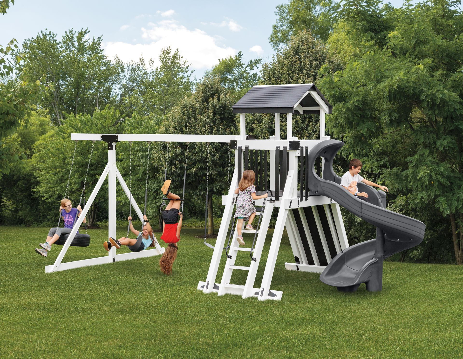 Children playing on a swing set in a grassy yard.