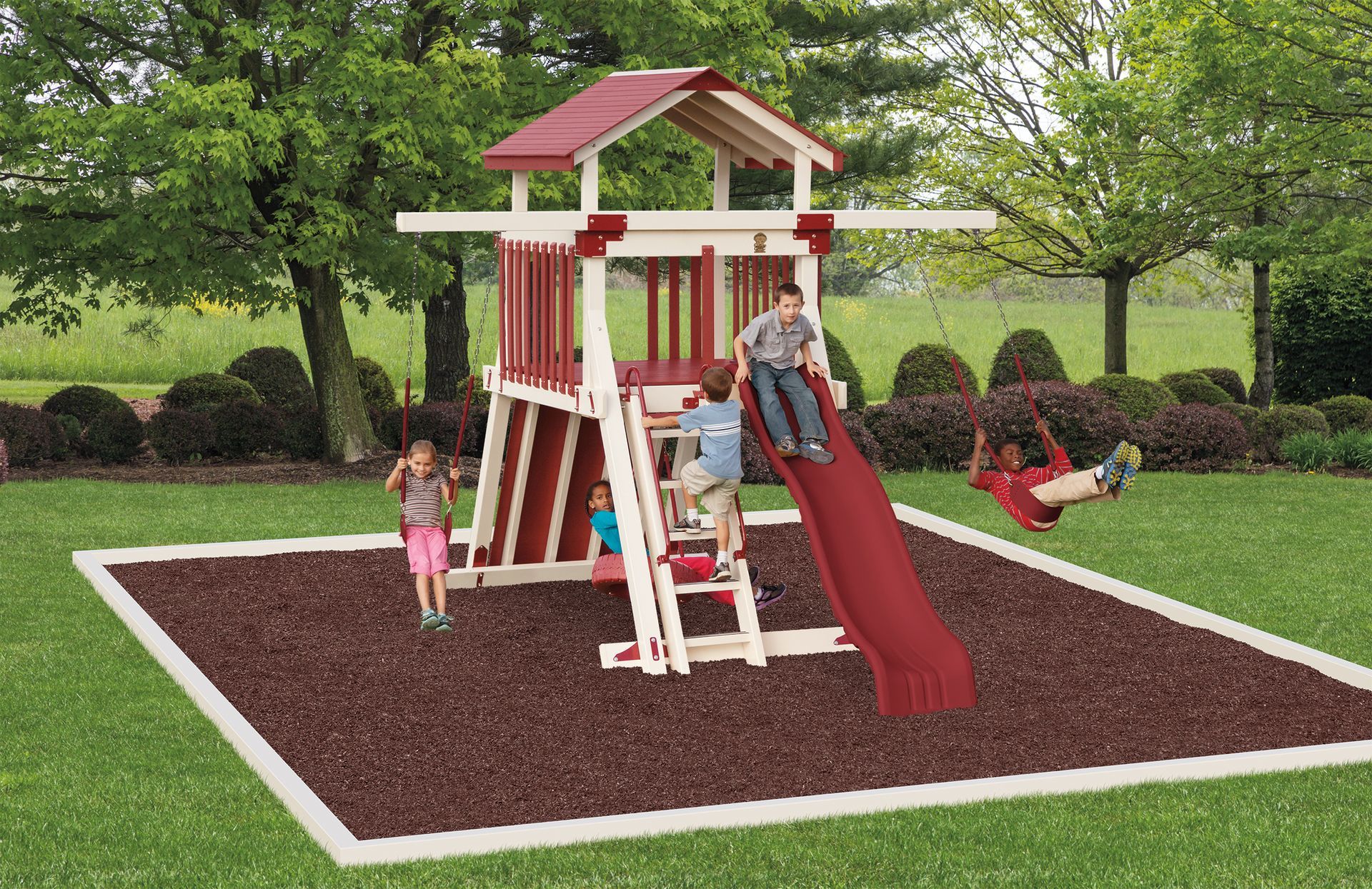 Children playing on a red and white wooden playset with slide, ladder, and swing set on mulch.