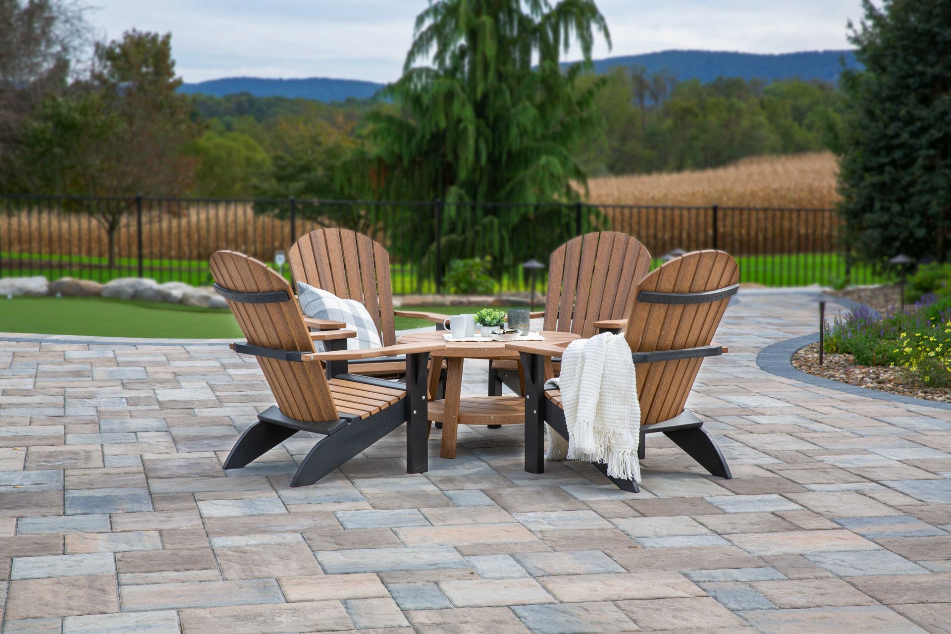 Outdoor seating area with four Adirondack chairs around a small table on a stone patio.