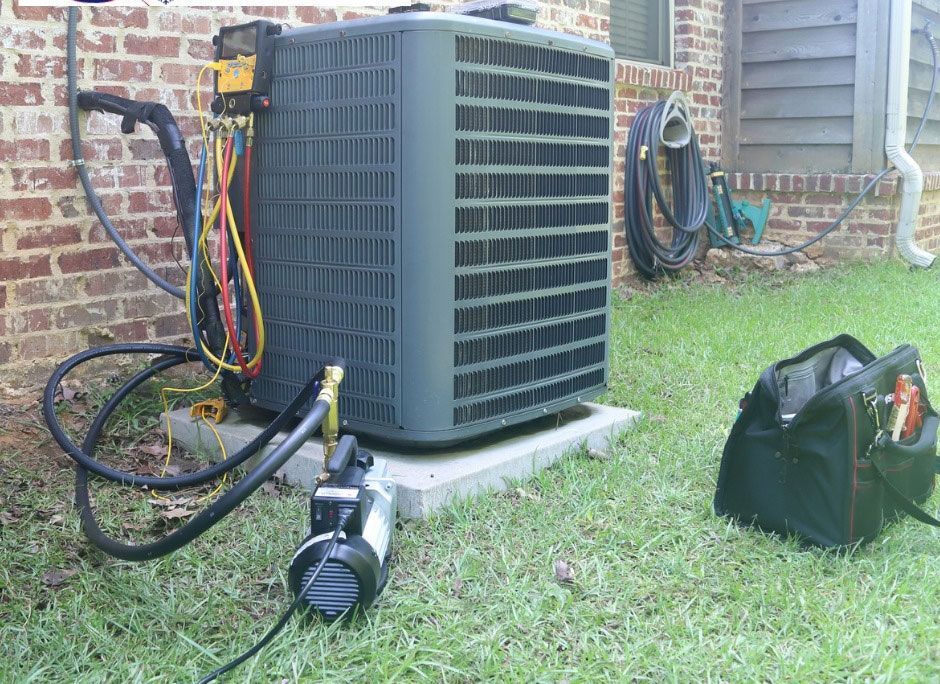 An air conditioning unit being serviced outdoors, with tools, hoses, and vacuum pump.