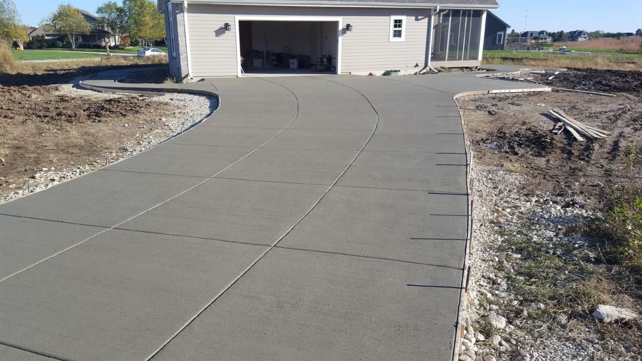 a concrete driveway leading to a garage with a house in the background