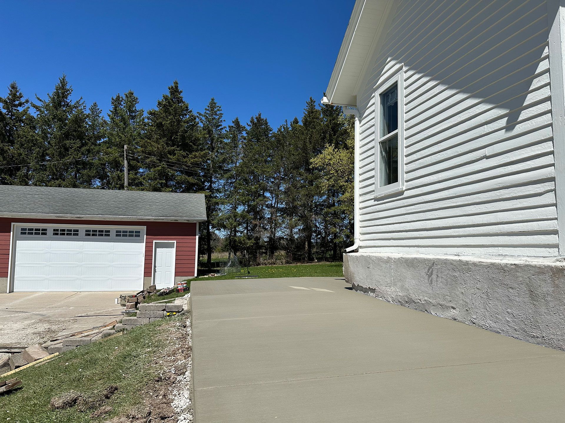 A white house with a red garage and a concrete driveway