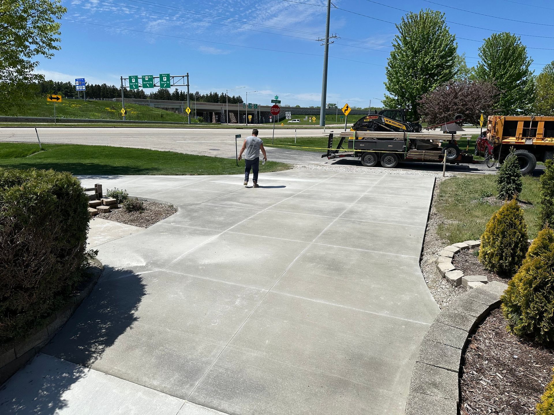A man is standing on a concrete driveway next to a truck
