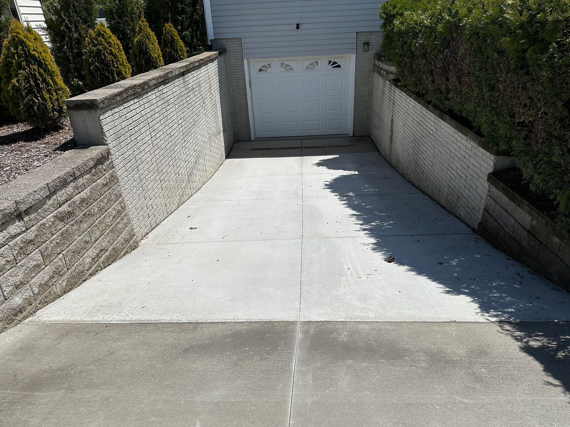 A concrete driveway leading to a white garage door