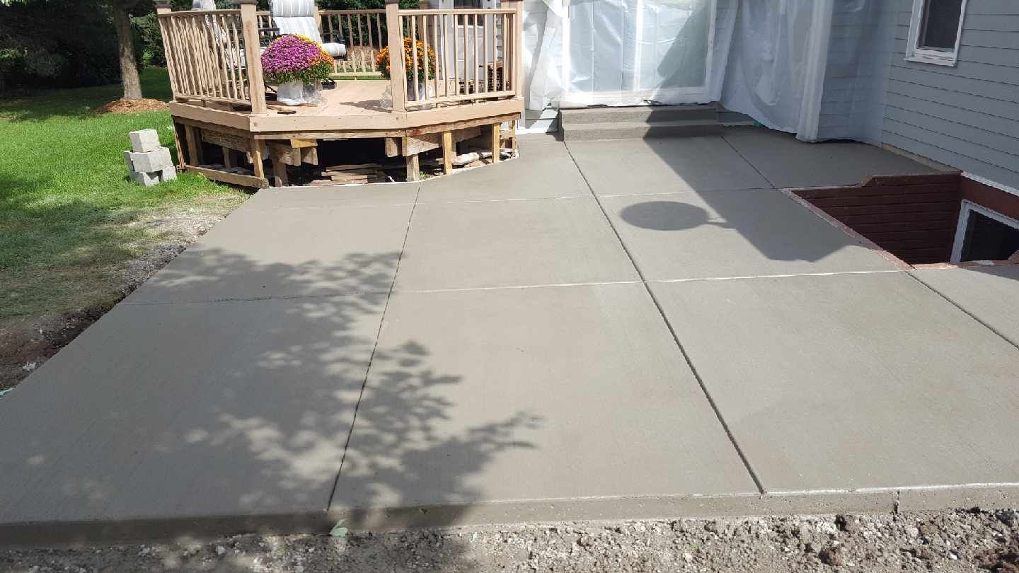 a concrete patio with a wooden deck in the background