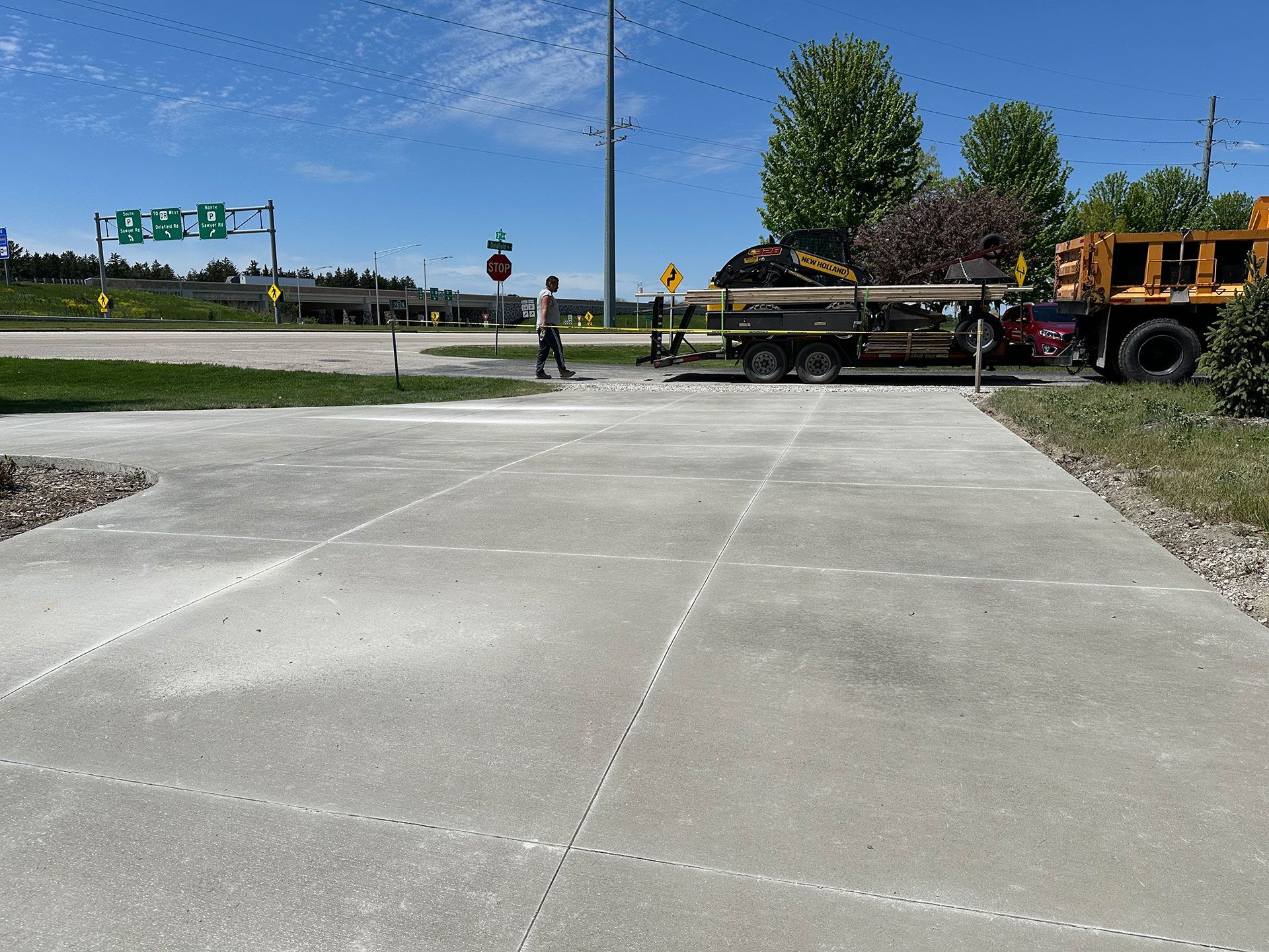A concrete driveway with a yellow truck in the background
