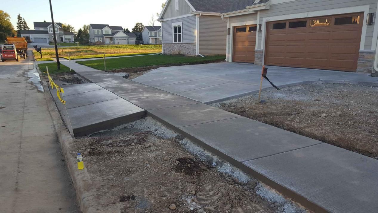 a concrete sidewalk and driveway are being built in front of a house