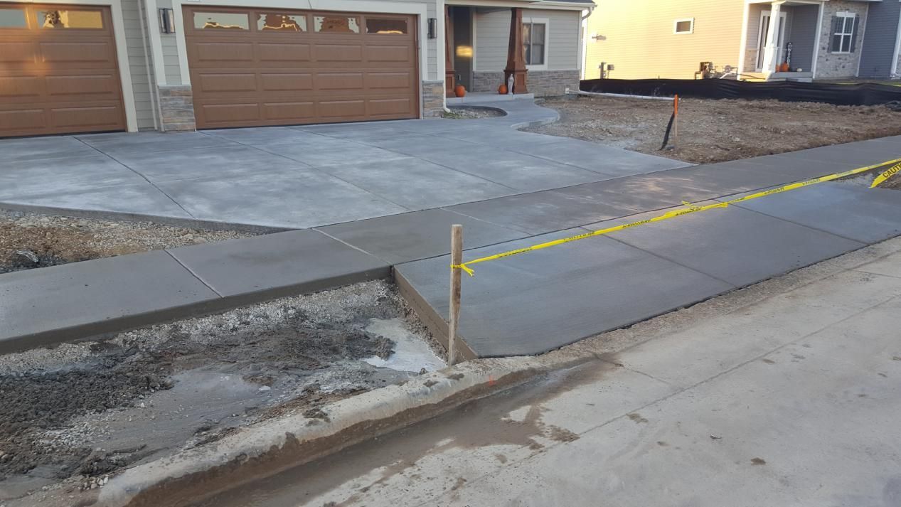 a concrete driveway is being built in front two garage doors