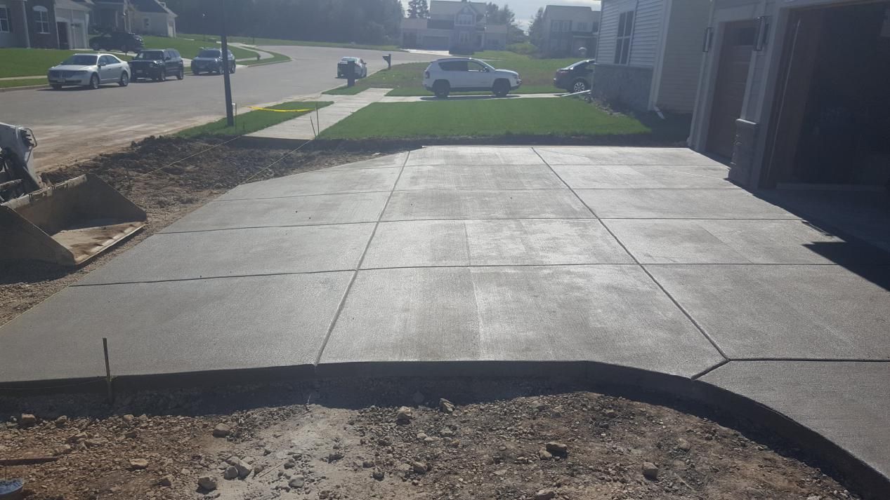 a wide concrete driveway is being built in front of a house