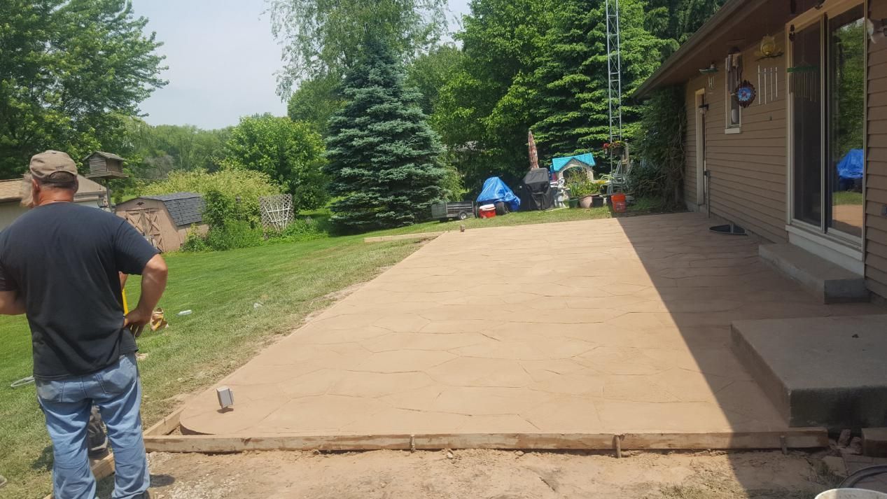 a man is standing in front of a house looking at a concrete patio being built