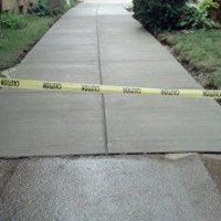 a concrete driveway with a yellow caution tape