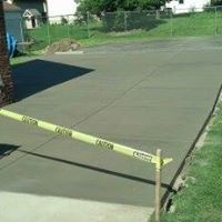 a concrete patio is being built next to a fence