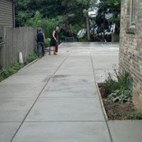 a couple of people standing on a concrete flooring next to a brick building