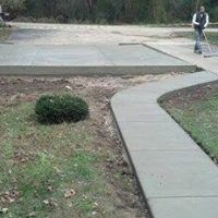 a man is walking down a sidewalk next to a concrete driveway