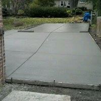 a concrete driveway is being built next to the lawn