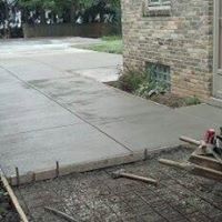 A concrete driveway is being built in front of a brick house.