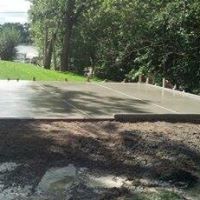 A concrete driveway with trees in the background and a lake in the background.