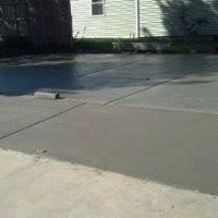A concrete driveway with a white house in the background.