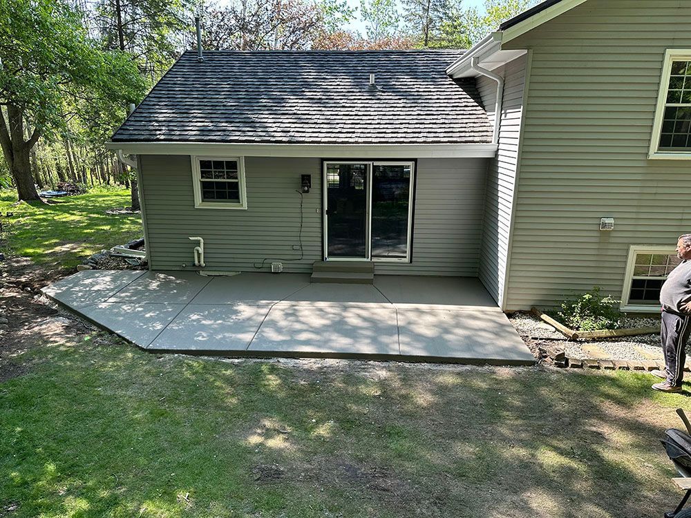 A man is standing in front of a house with a patio in front of it.