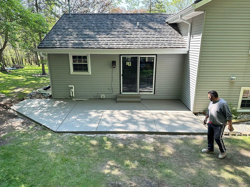 A man is standing in front of a house with a patio in front of it.