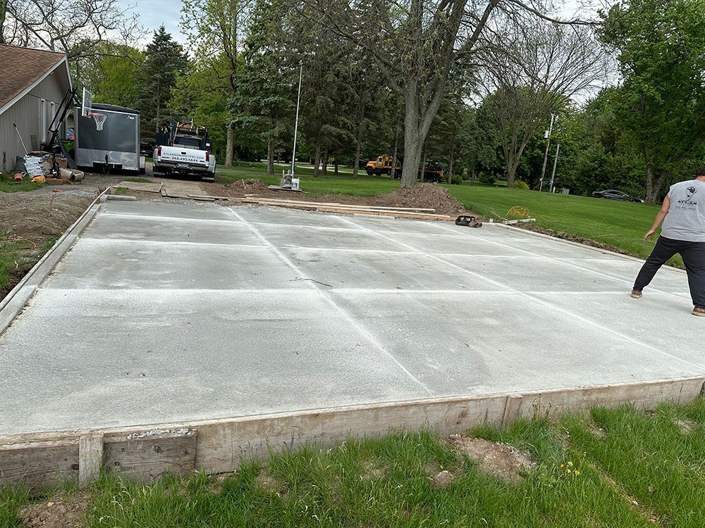 A man is standing on a concrete driveway in front of a house.