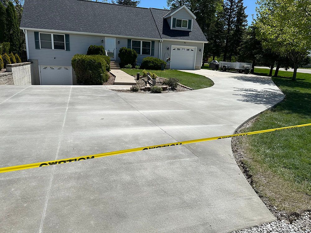 A concrete driveway in front of a house with a yellow tape around it