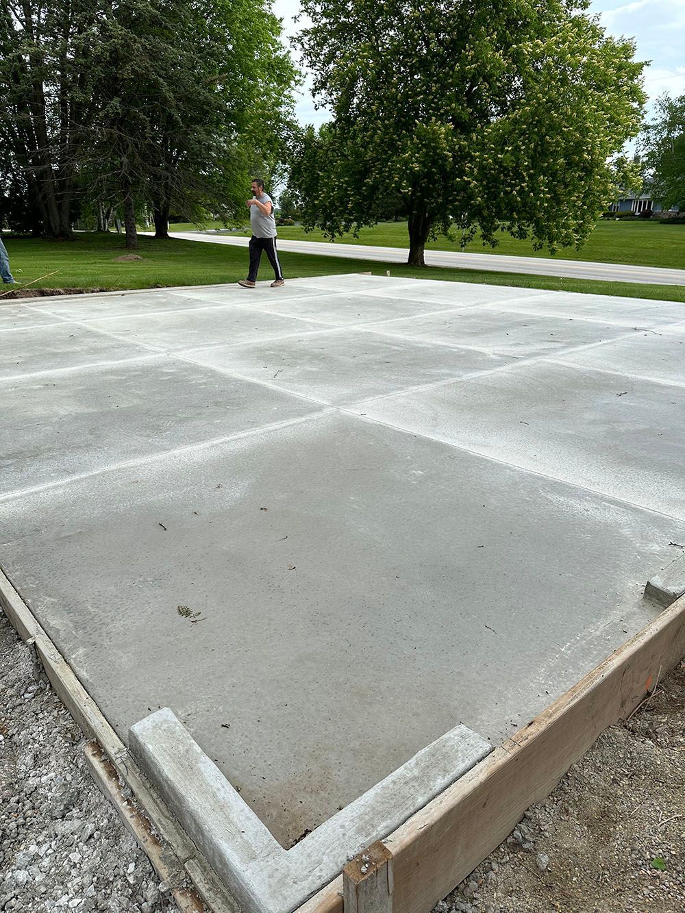 A woman is walking on a concrete floor in a park.