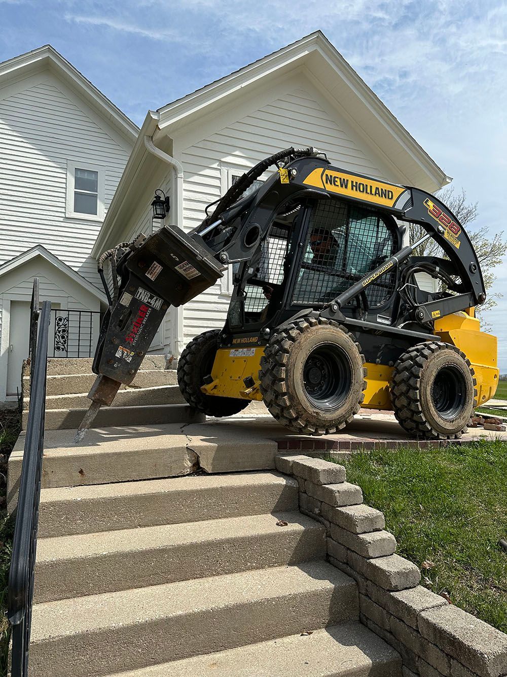 A bulldozer is sitting on top of a set of stairs in front of a house.