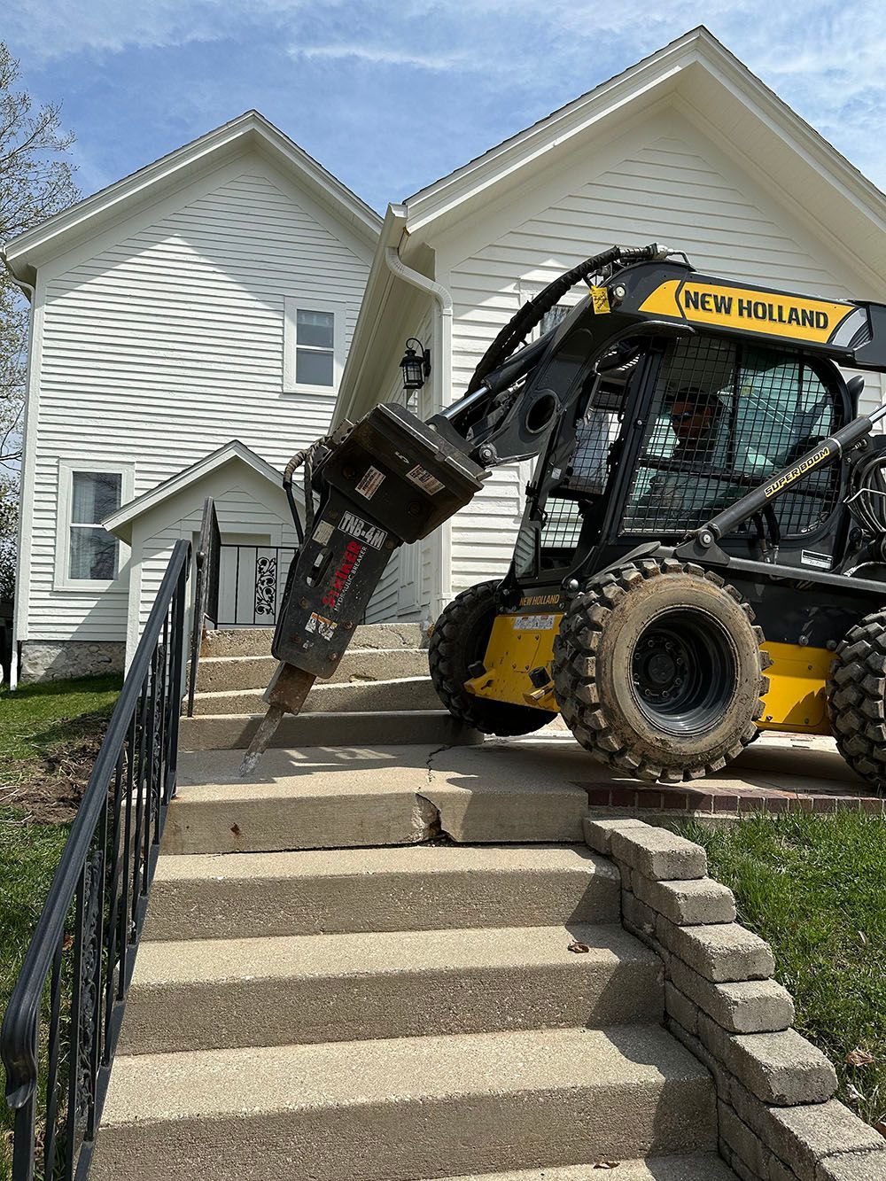 A bulldozer is driving down a set of stairs in front of a house.