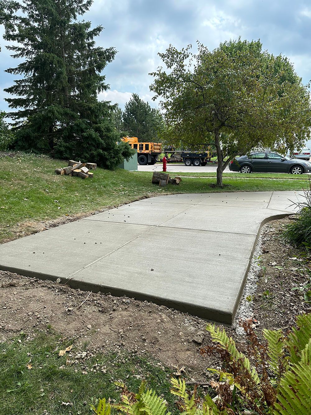 A concrete driveway with a yellow school bus parked in the background.