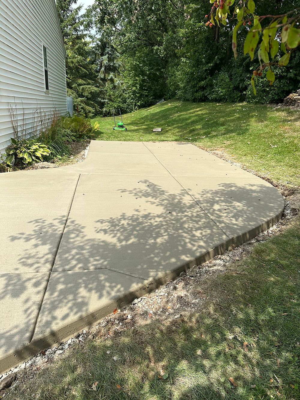 A concrete driveway leading to a house with trees in the background.