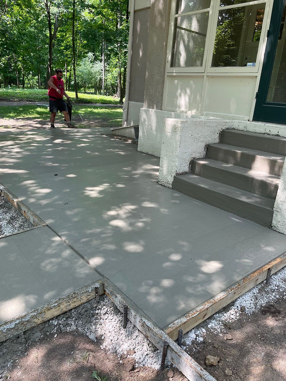 A man is standing on a concrete sidewalk in front of a house.