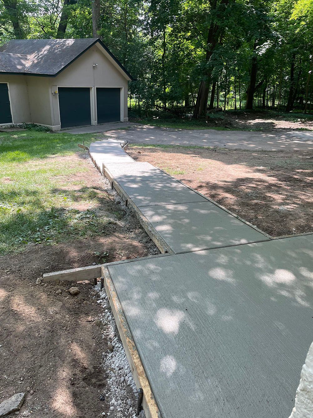 A concrete walkway is being built in front of a garage.