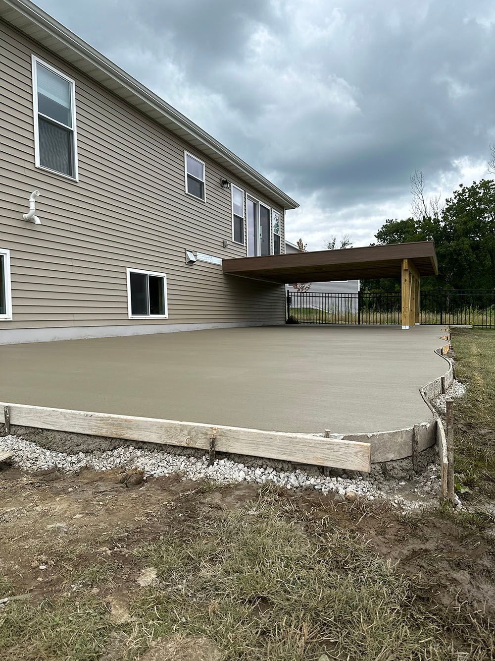 A concrete deck is being built in front of a house.