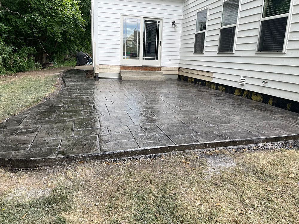 A concrete patio in front of a white house.