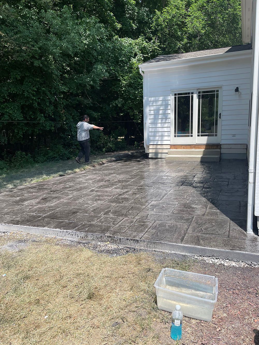 A man is standing on a concrete patio in front of a house.