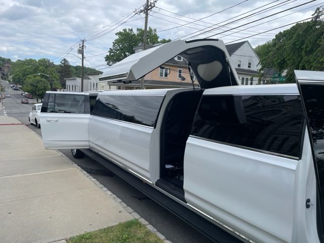 White limousine with doors open on a city street.